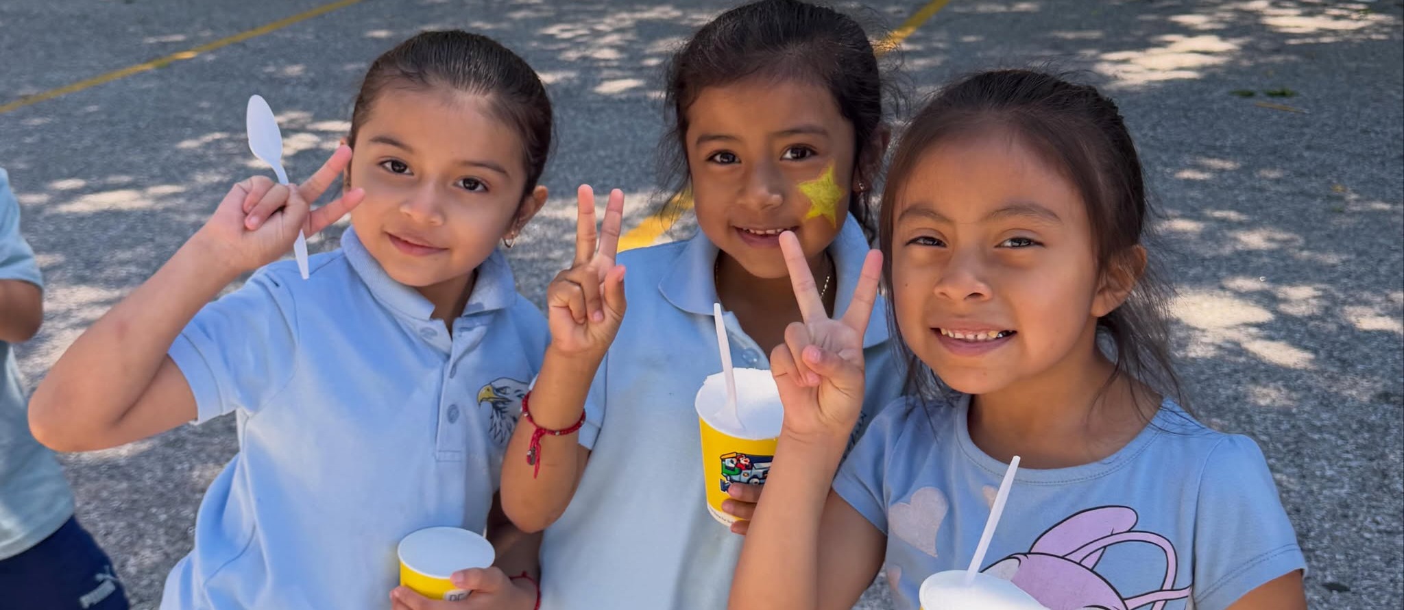 Three students posing for the camera eating ice cream