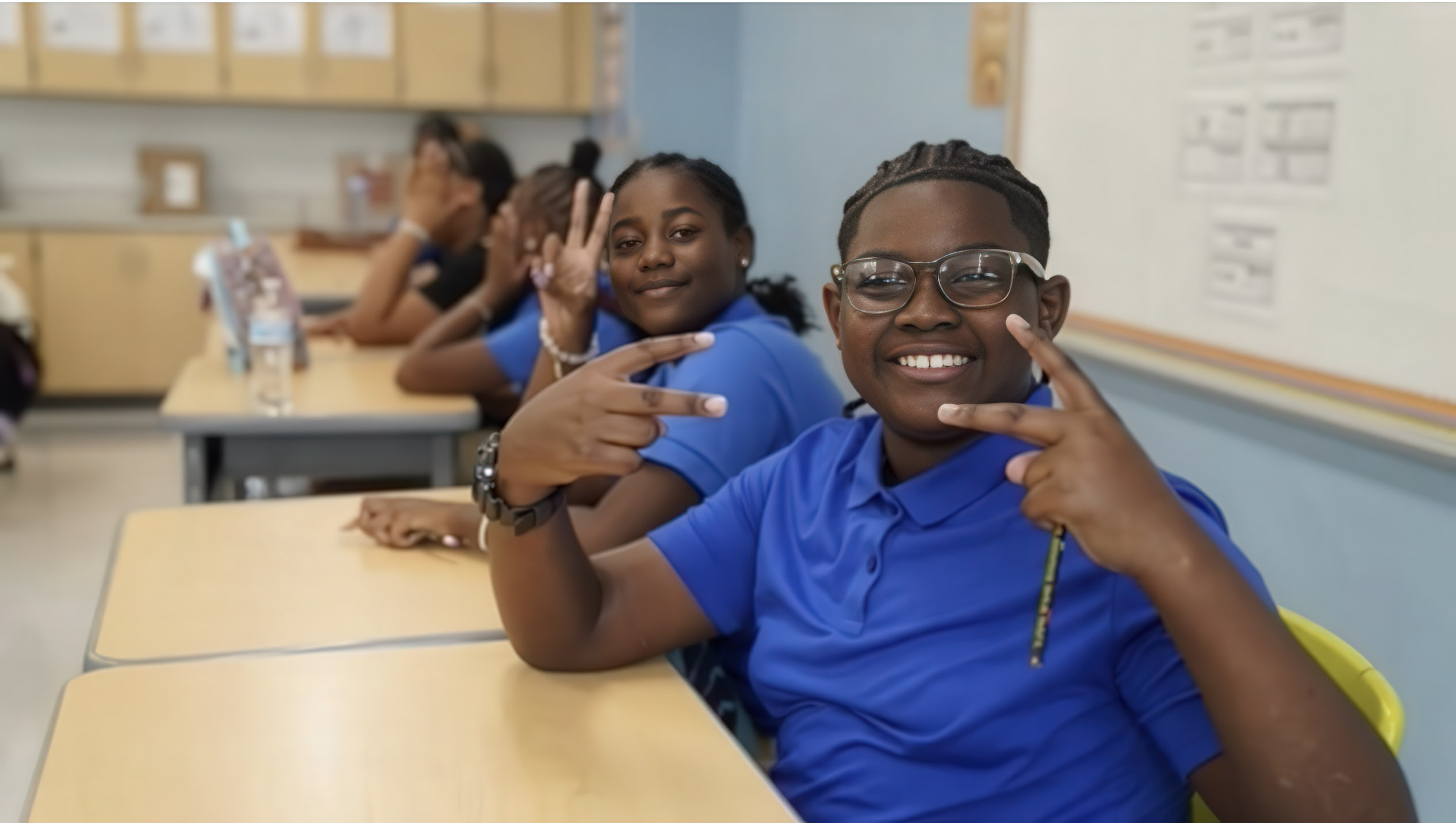 Student sitting at their desk with peace sign