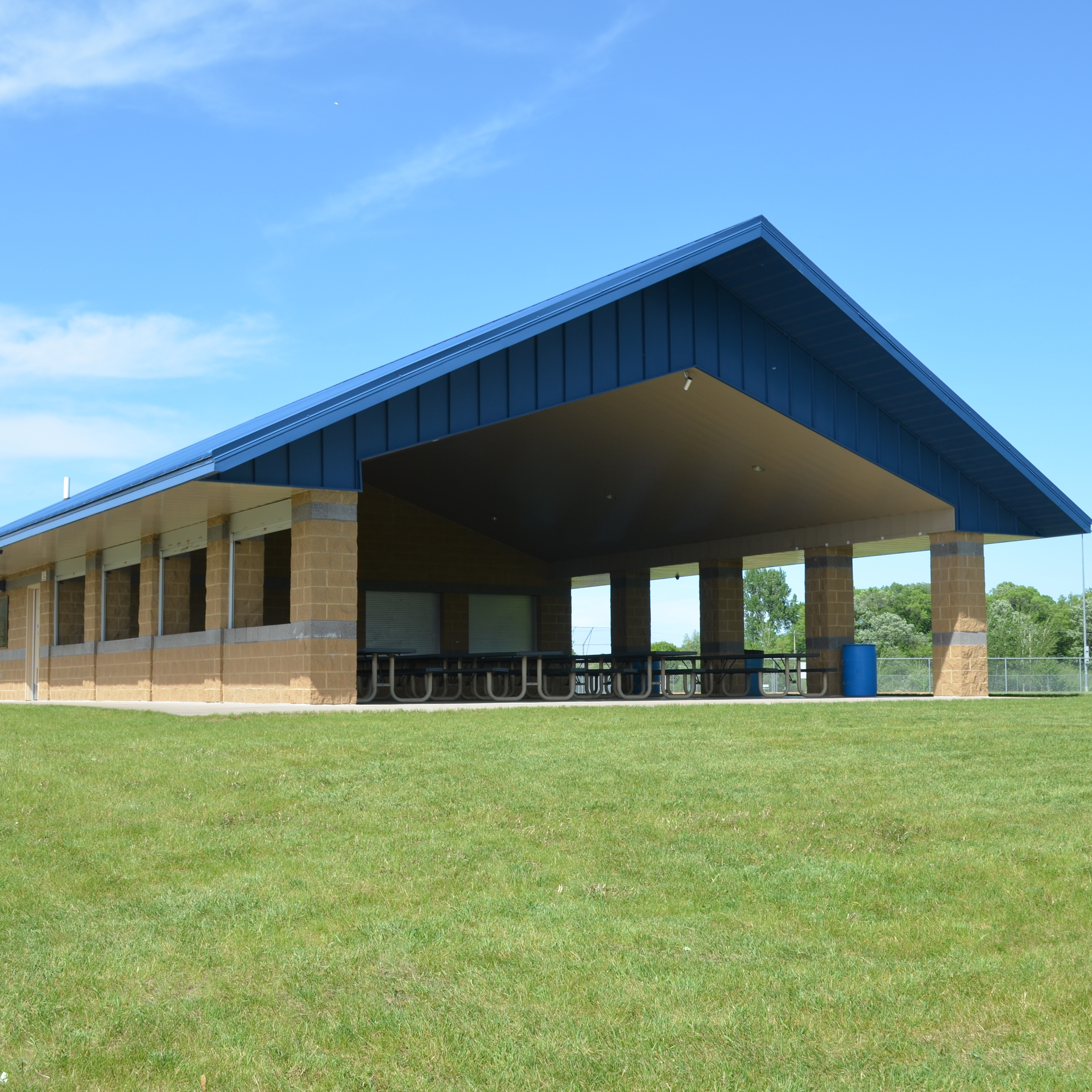 a pavilion with a blue roof on green grass