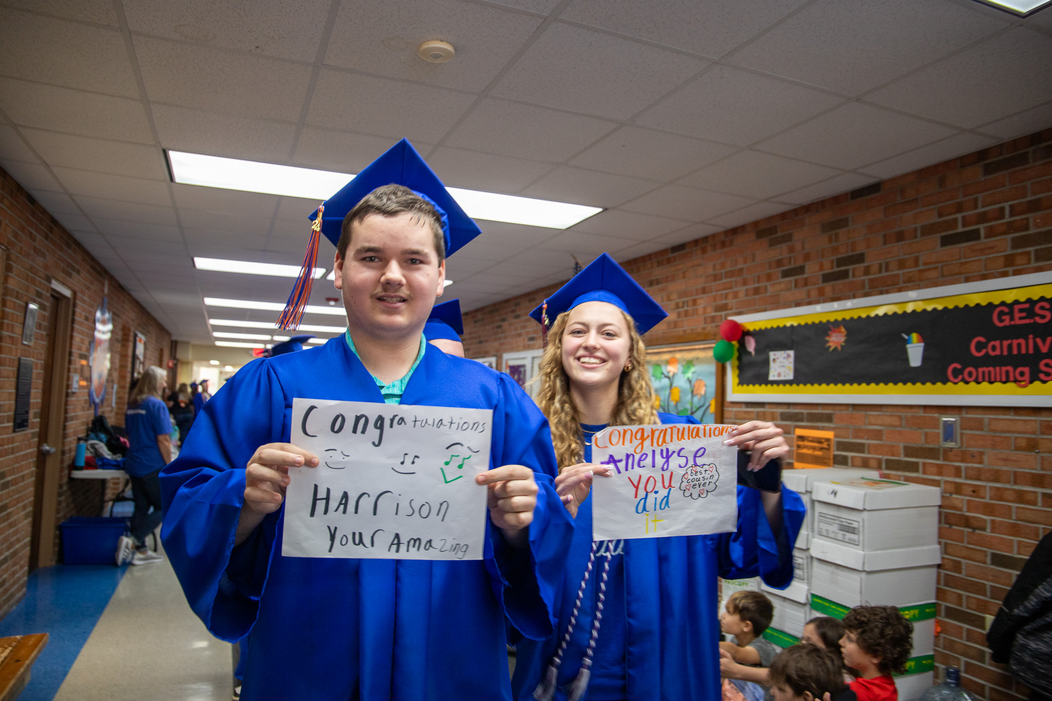 image of students in cap and gown holding signs
