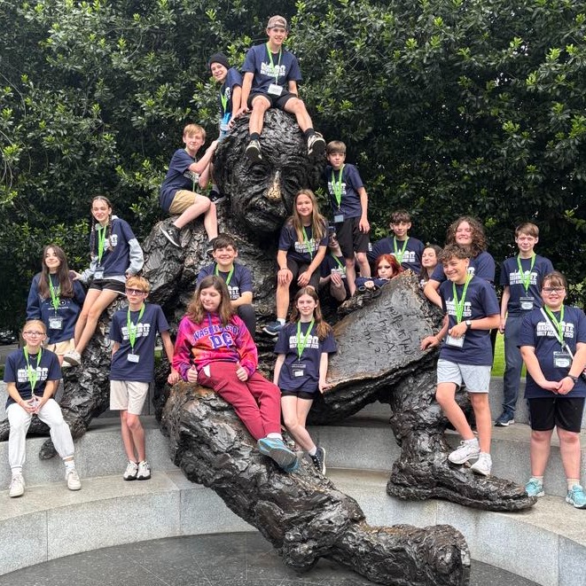 Students pose on sculpture of Albert Einstein in Washington, D.C.