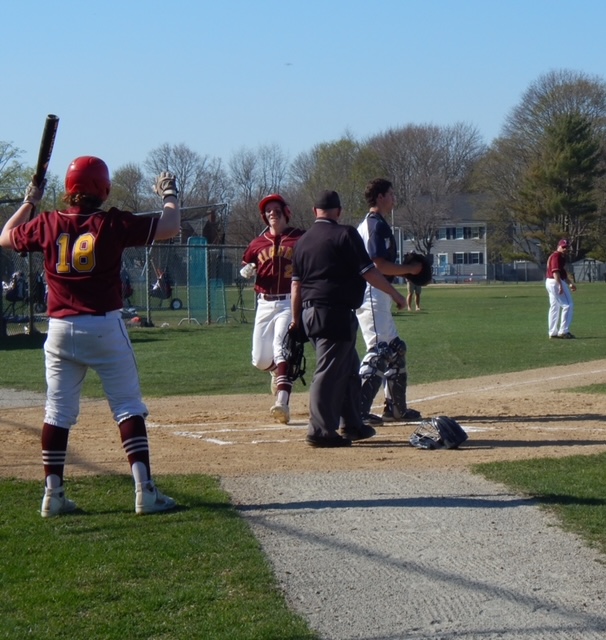 players in maroon jerseys look on as umpire speaks 