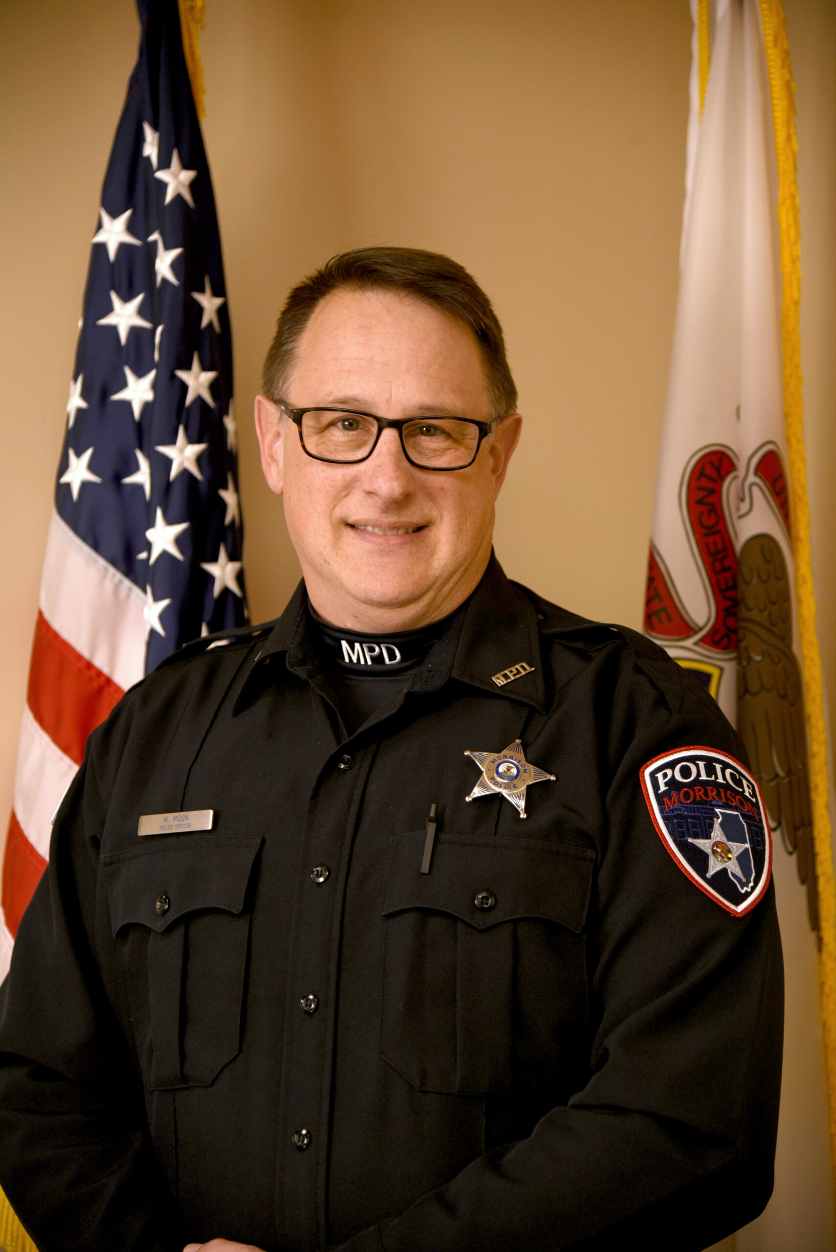 image of police officer standing in front of the American flag