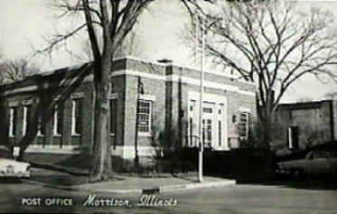 black and white photo of the exterior of a post office with flag pole out front