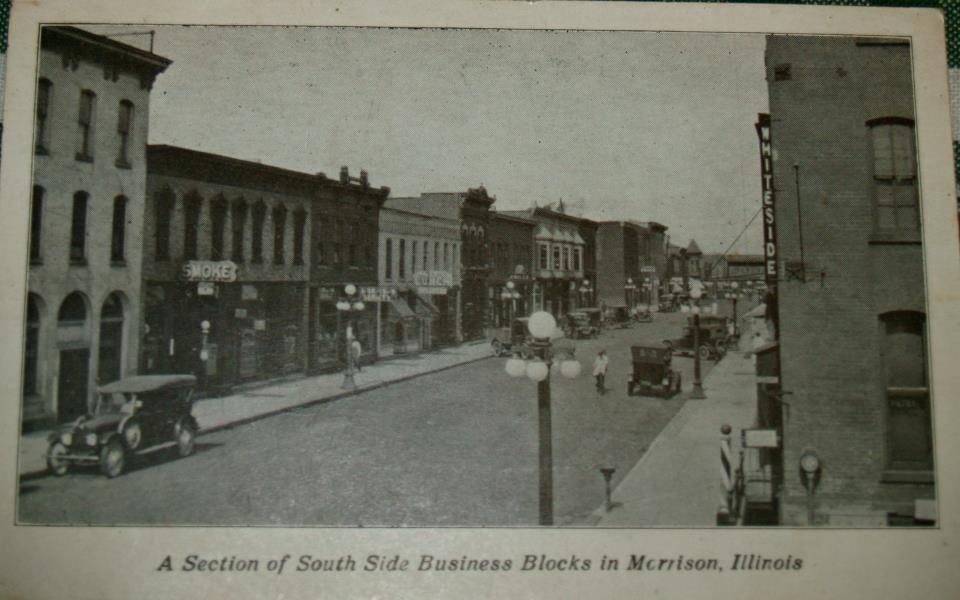 black and white photo of main street with antique cars driving the road