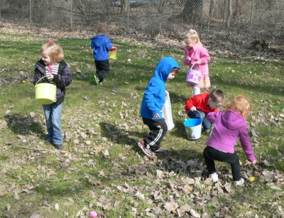 kids run around a lawn looking for Easter eggs