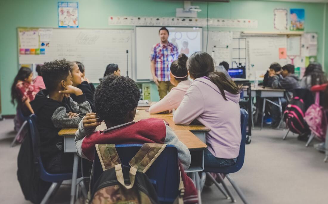 teacher standing in front of a group of students sitting at a table