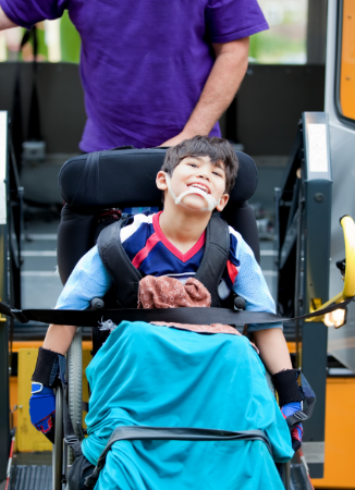 student in wheelchair being assisted by bus driver