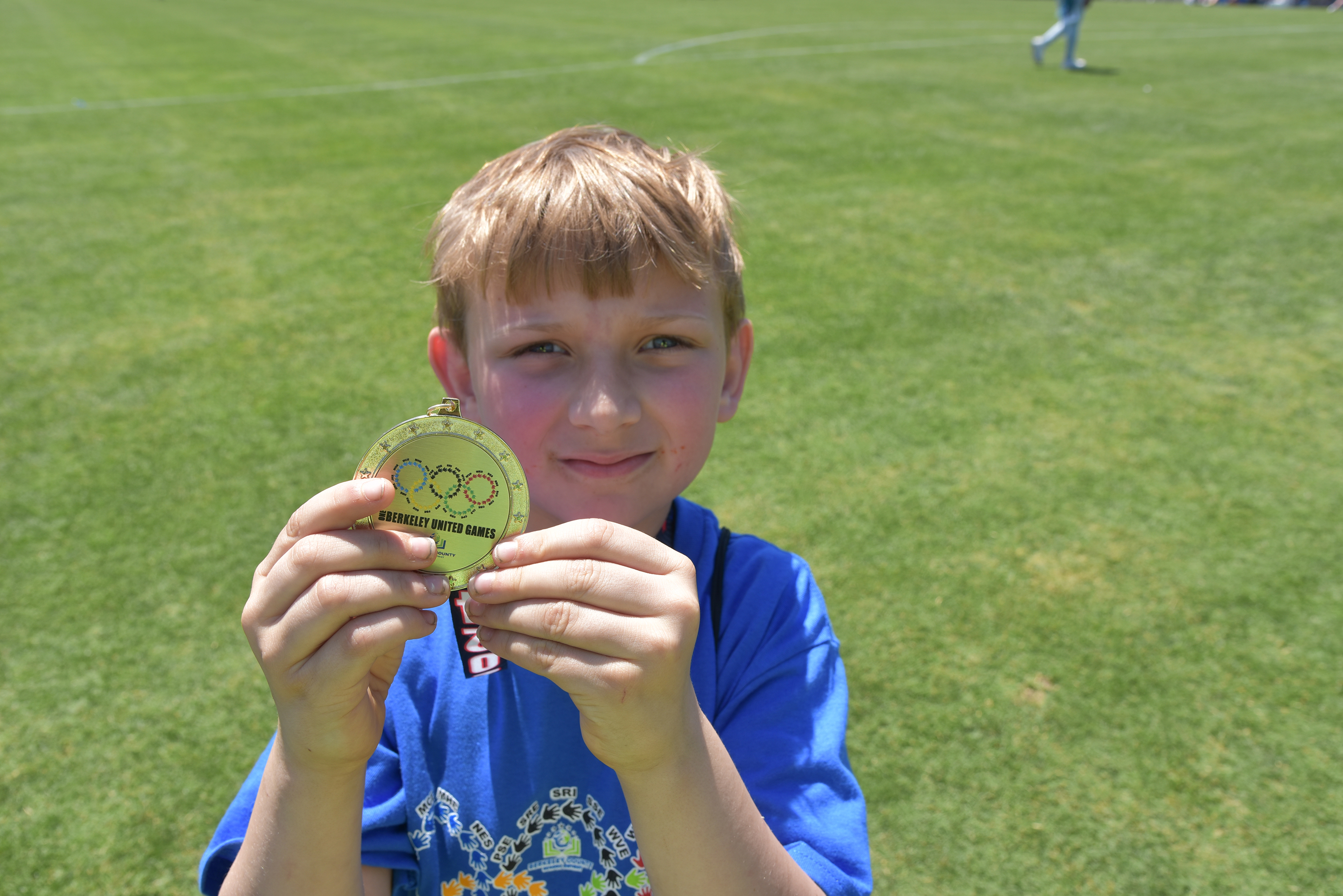 boy holding medal up to camera