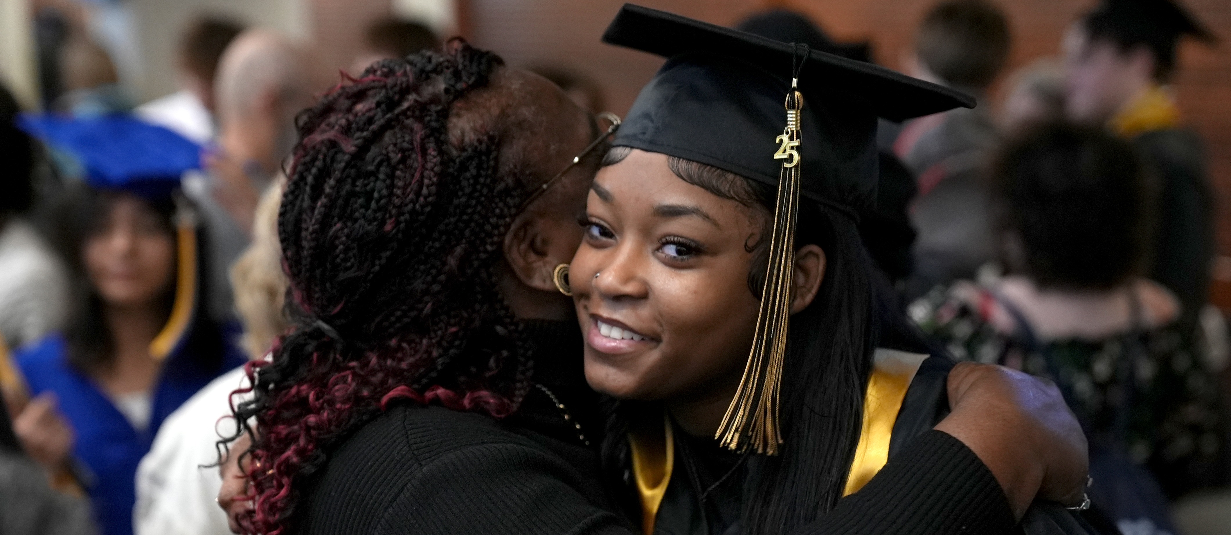 student smiling while being  hugged during graduation