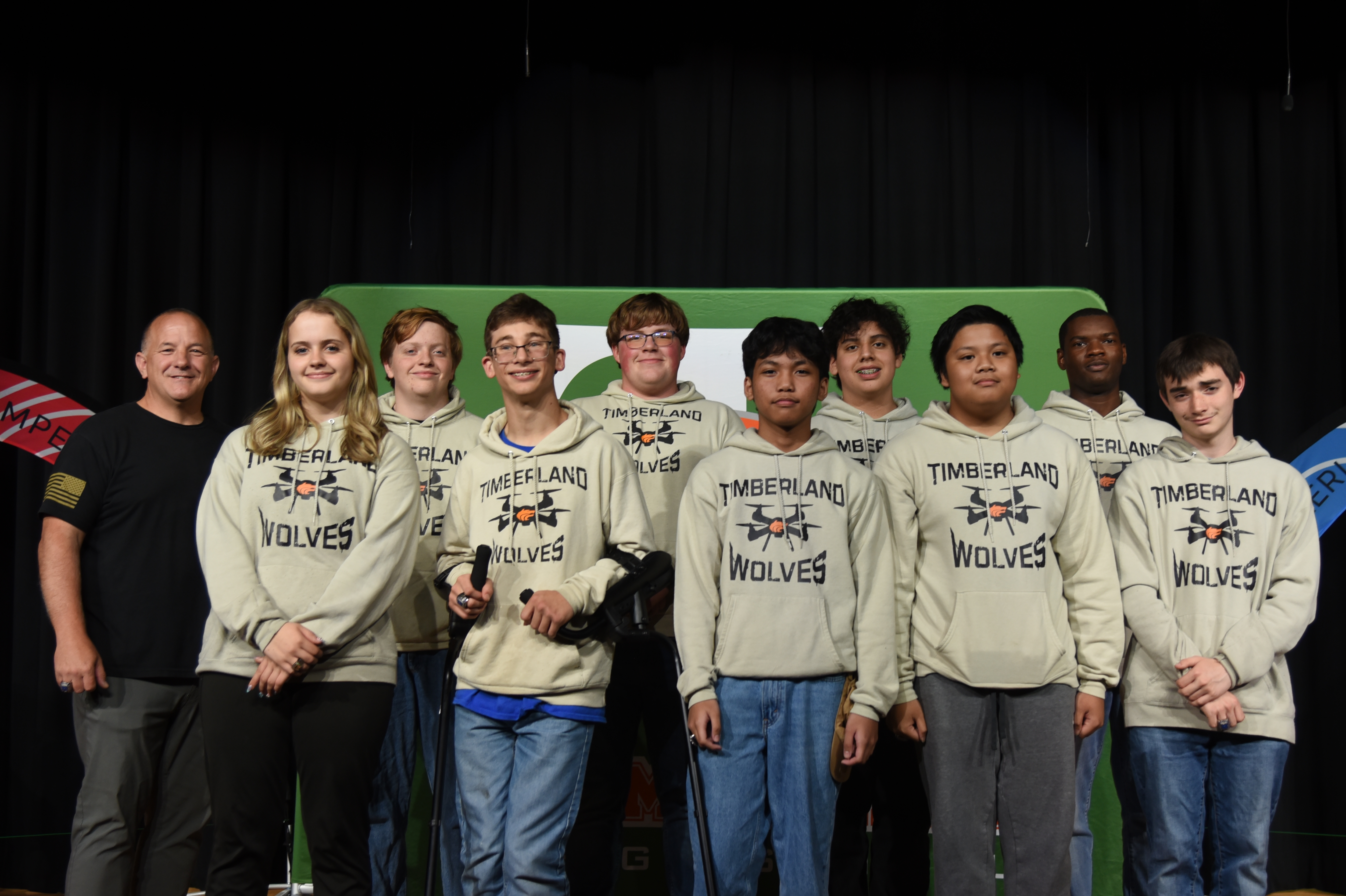 A group of young people in matching hoodies with "Wolves" on them, standing on a stage.