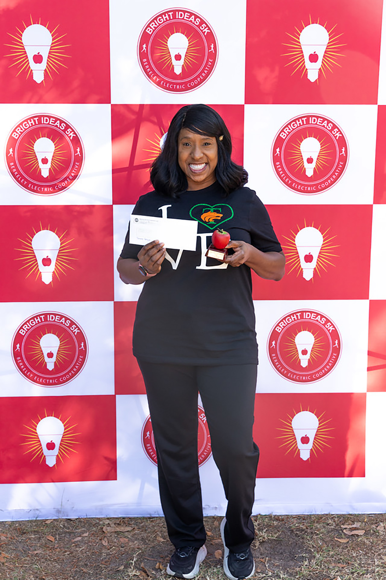 Person holding an envelope and apple in front of a red and white light bulb pattern.