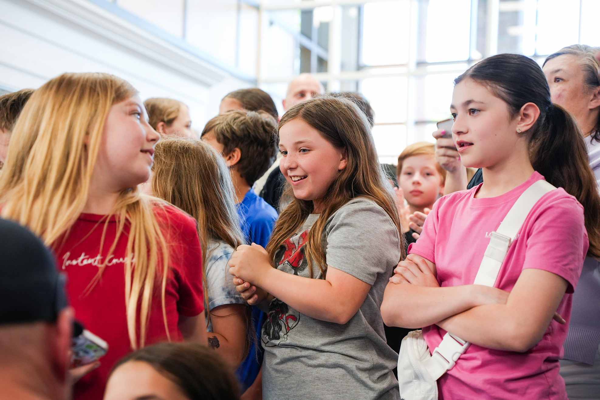 A group of children, some with blonde hair, engaged in conversation in an indoor setting.
