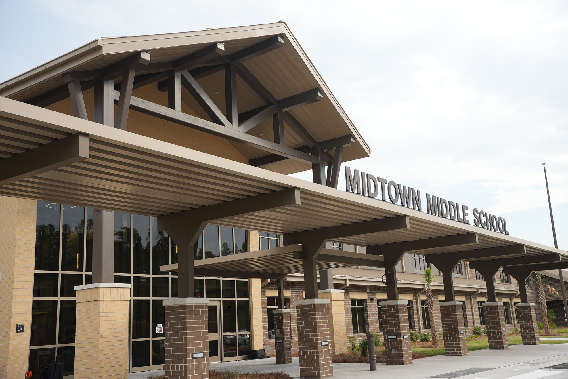 A school entrance with a triangular roof, large windows, and a sign that reads "MIDTOWN MIDDLE SCHOOL".