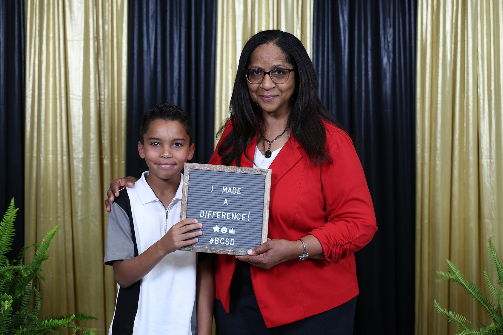 A woman and a child standing next to each other, holding a chalkboard with a message.