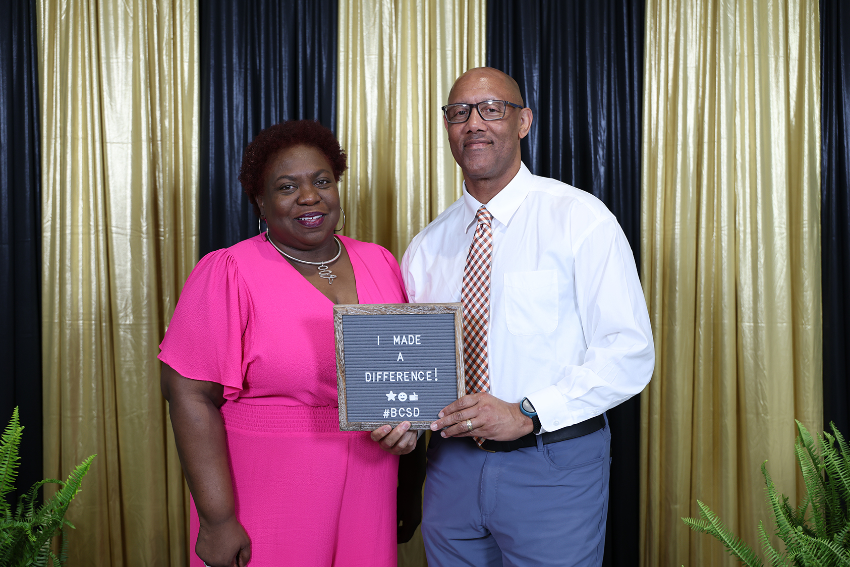 A man and woman stand next to each other, holding a framed plaque that reads, "I Made a Difference."