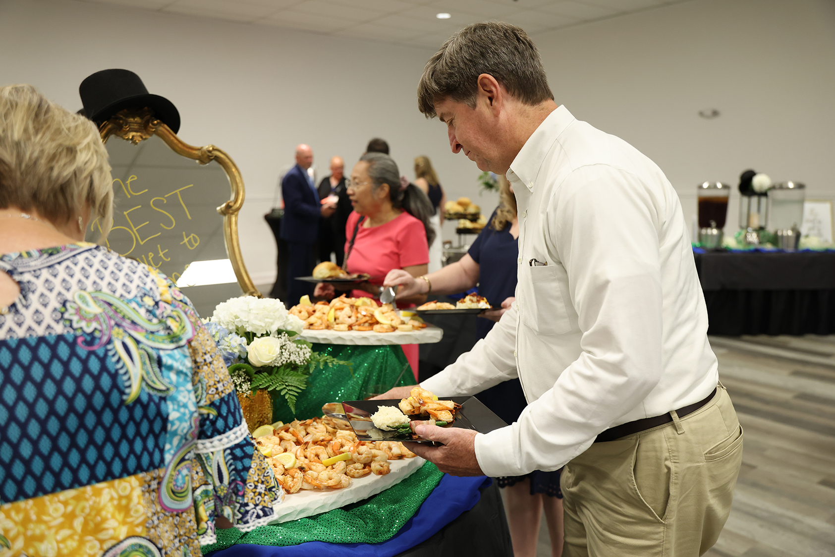 A man serving food at a table; a woman watches. An event with tables and guests.