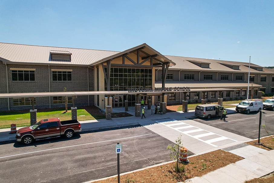 Exterior of a school building with a red pickup truck and other vehicles parked in front.
