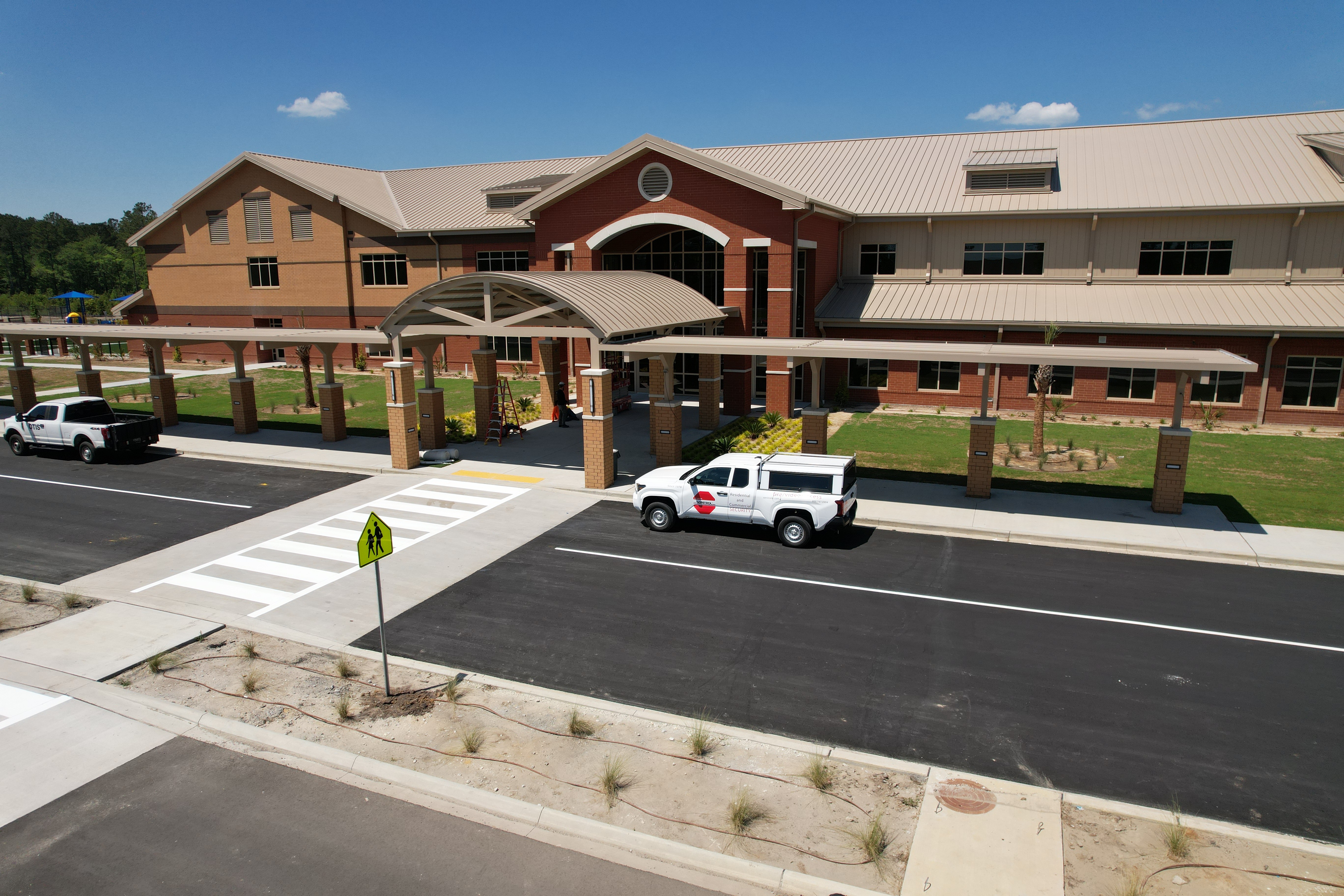 Exterior of a modern building with large windows and a roof. A pickup truck is parked in the driveway.