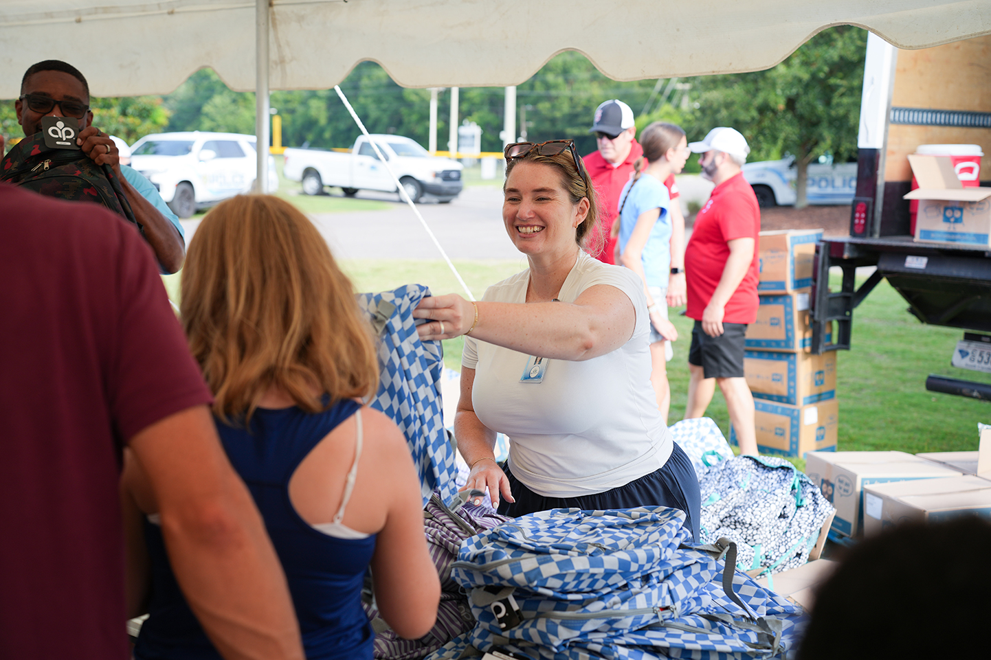 People gather in a tent, a woman in a white shirt smiles at a blue and white garment.