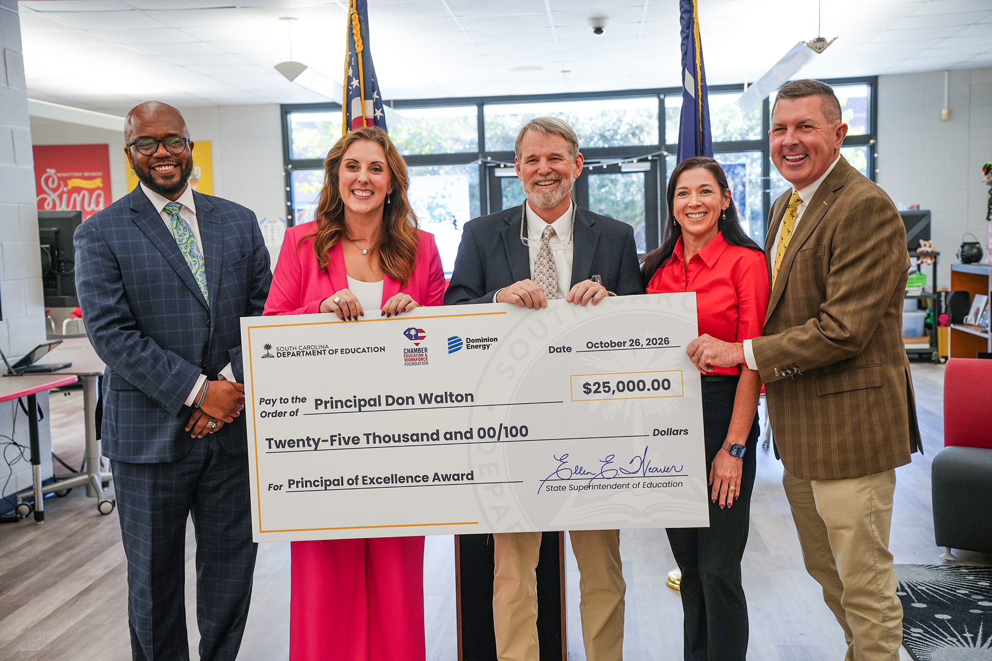 Five adults standing together holding a check with the words "Principal of the Year" on it.