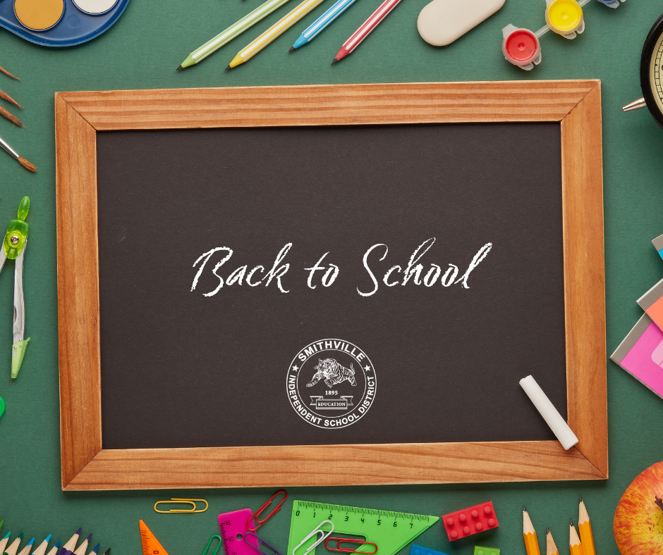 Blackboard says "Back to School" surrounded by pens, pencils, and school supplies on a green surface.