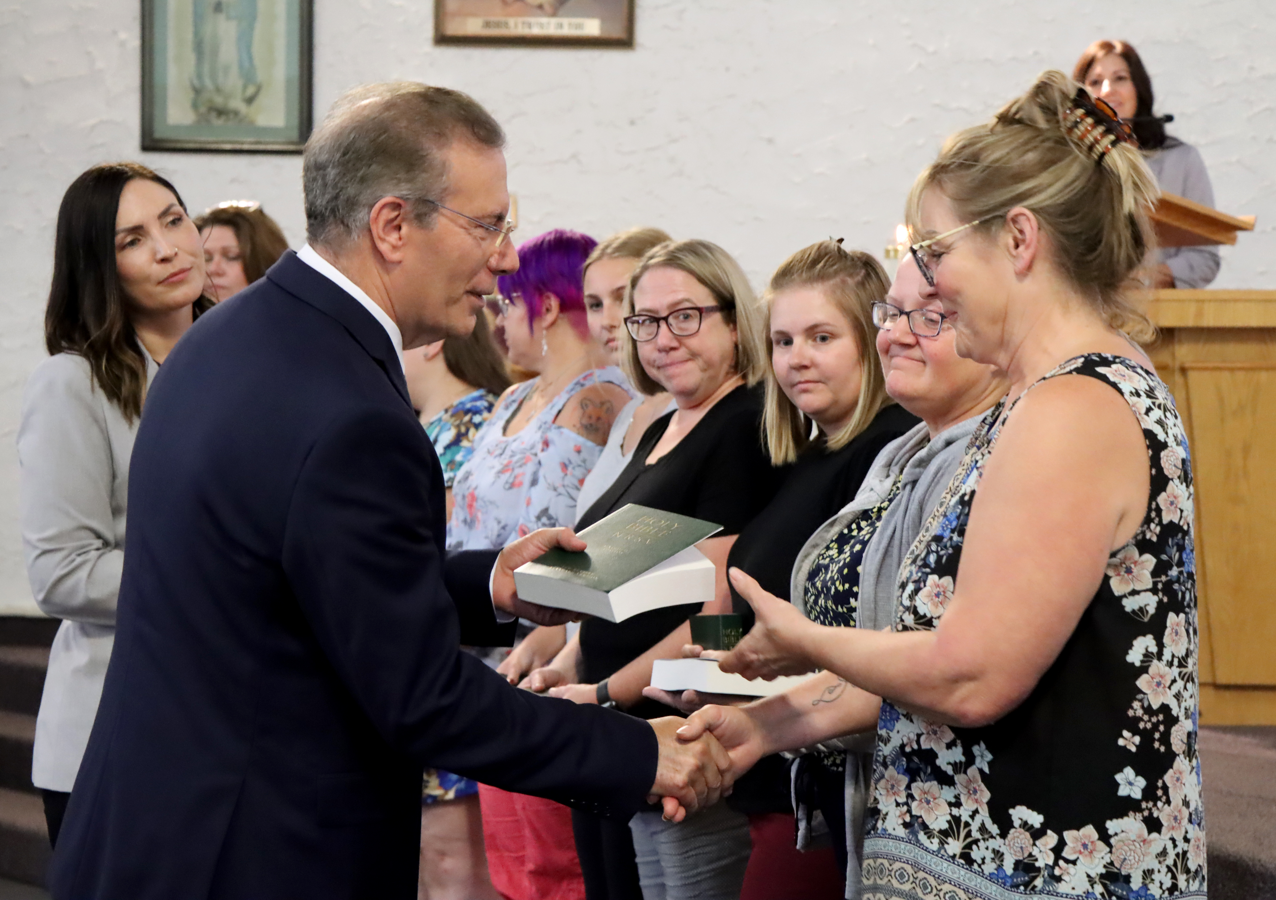 Man handing woman a bible and shaking her hand