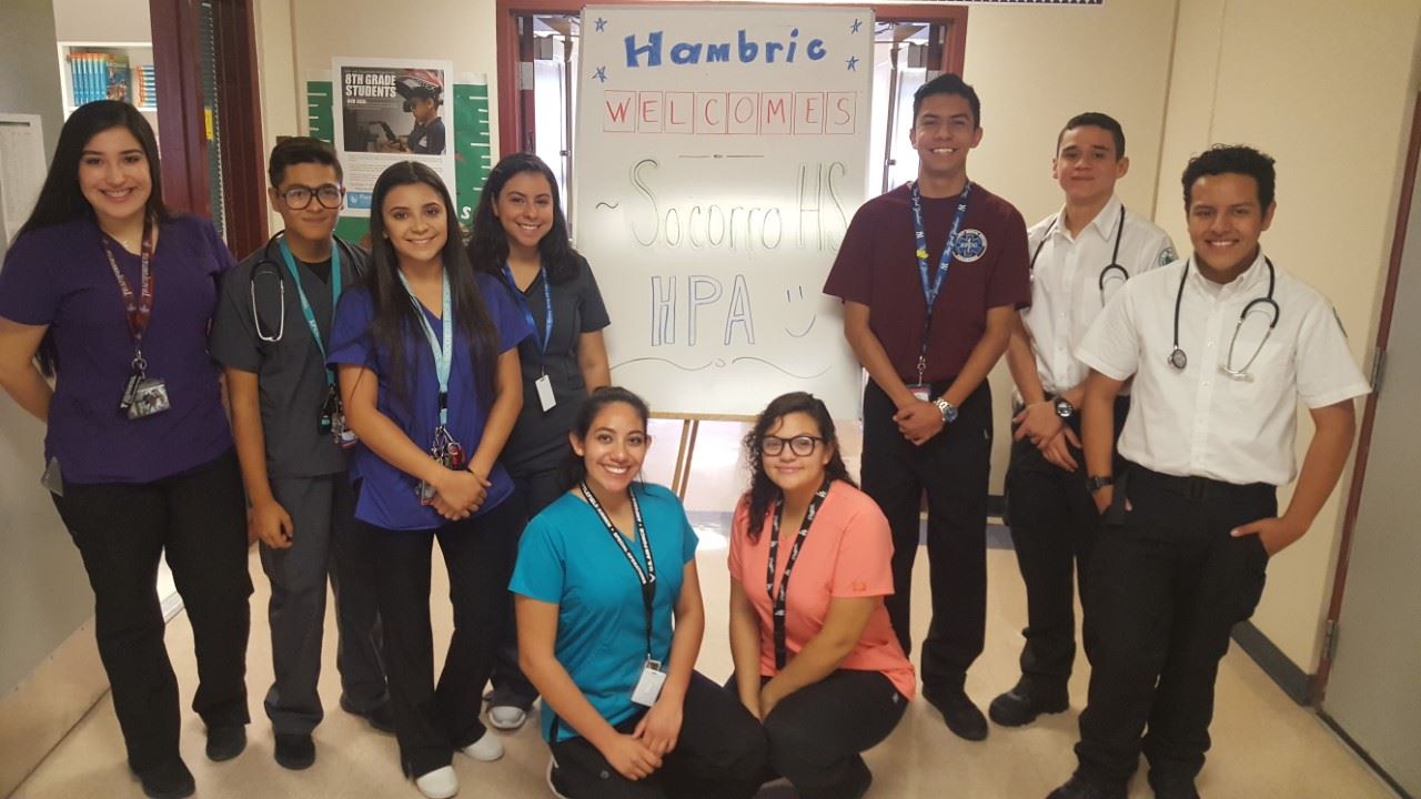 Group of health professional academy students in front of a white board that says "hambrie welcomes Socorro HS HPA"