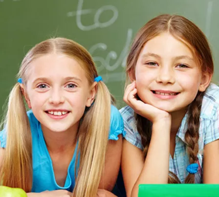 2 girls in  front of chaulk board