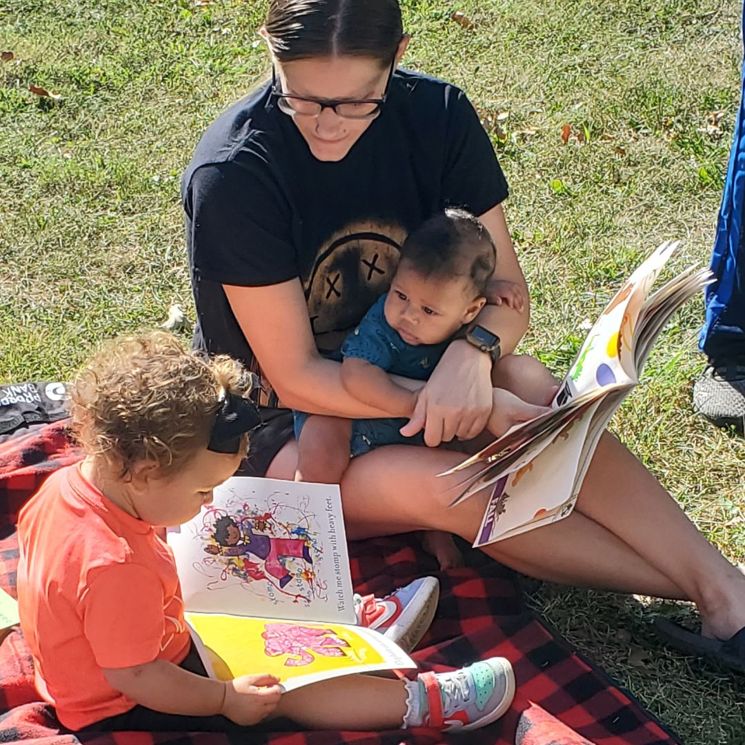 Parent reading to children in park