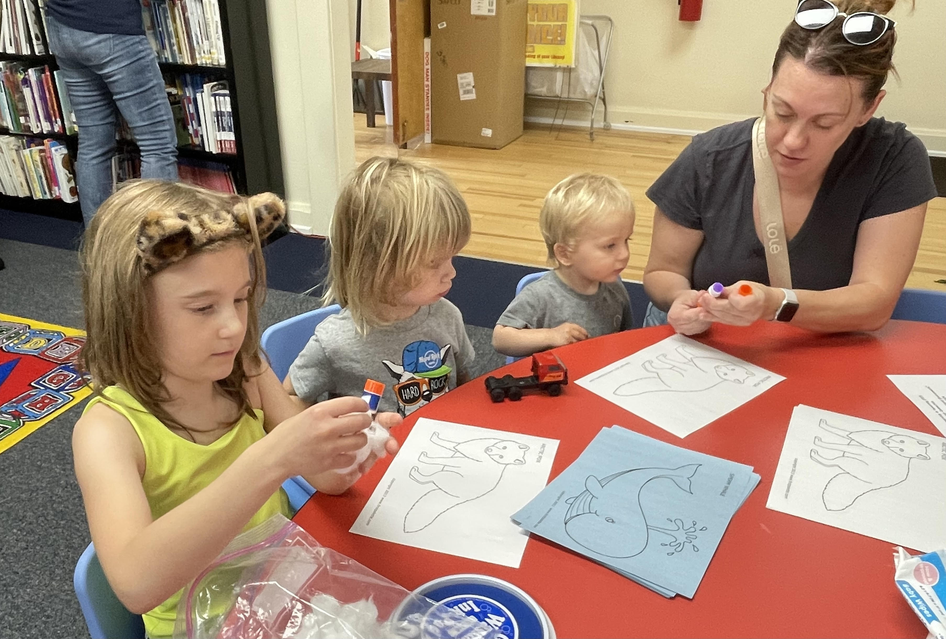 Parent pasting pictures with children at table