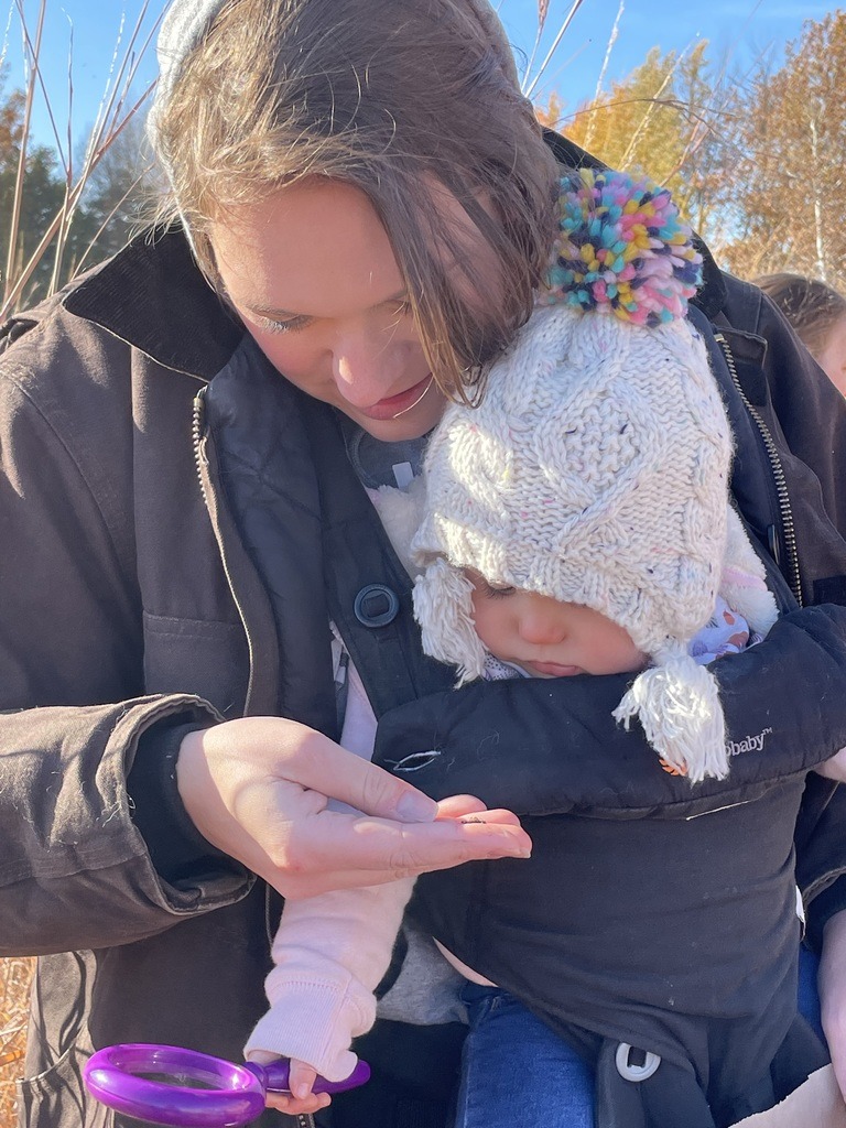 Parent and baby outside examining a seed