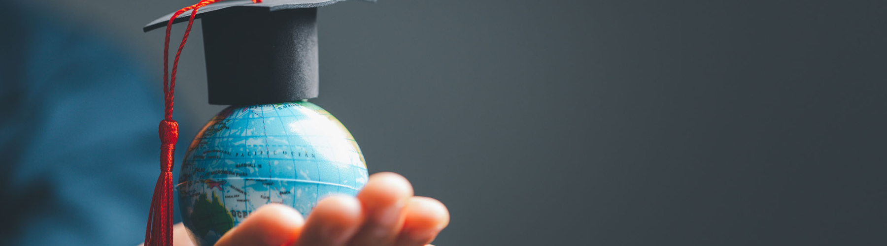 image of a hand on the left hand side holding a small globe with a cap on it
