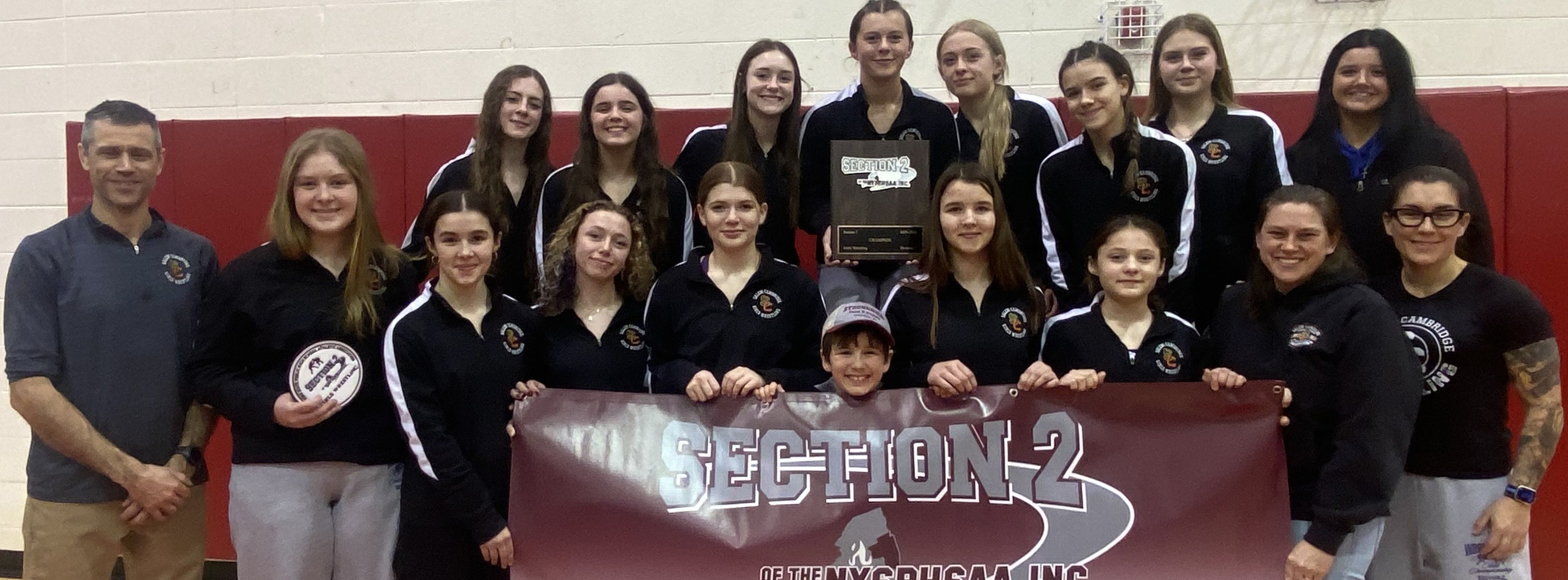 Varsity Girls Wrestling Team group photo, they are holding a  banner that says "Section 2 Champions"