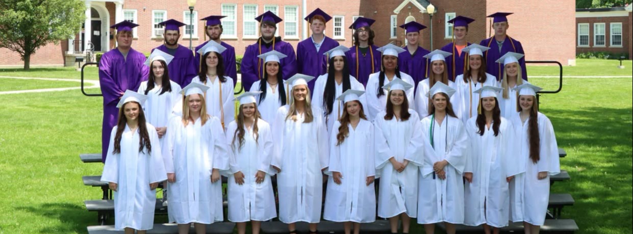 photo of graduating class, boys are wearing purple roles and girls are wearing white robes