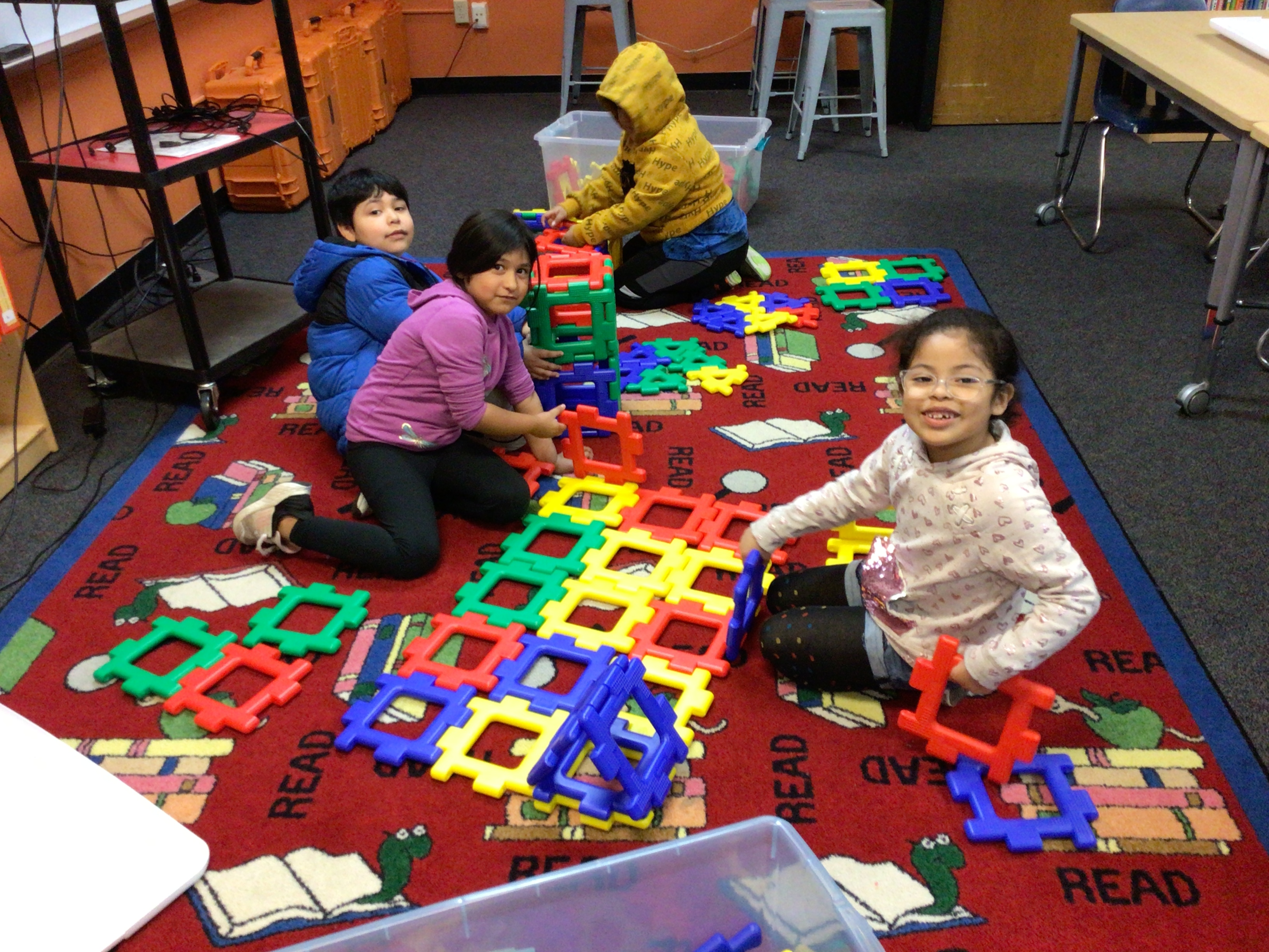 Students are starting to build with large plastic colorful blocks