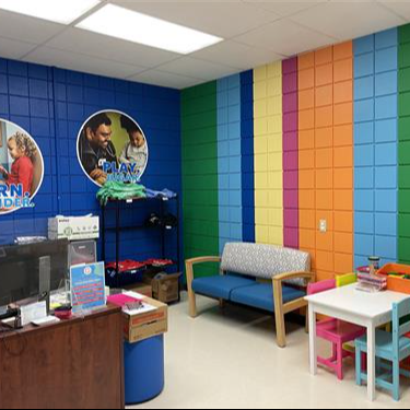 Clinic waiting room with rainbow-painted wall, seating, and front desk.