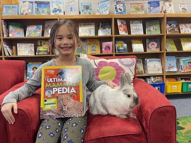 Student with donated book and Dewey the library bunny