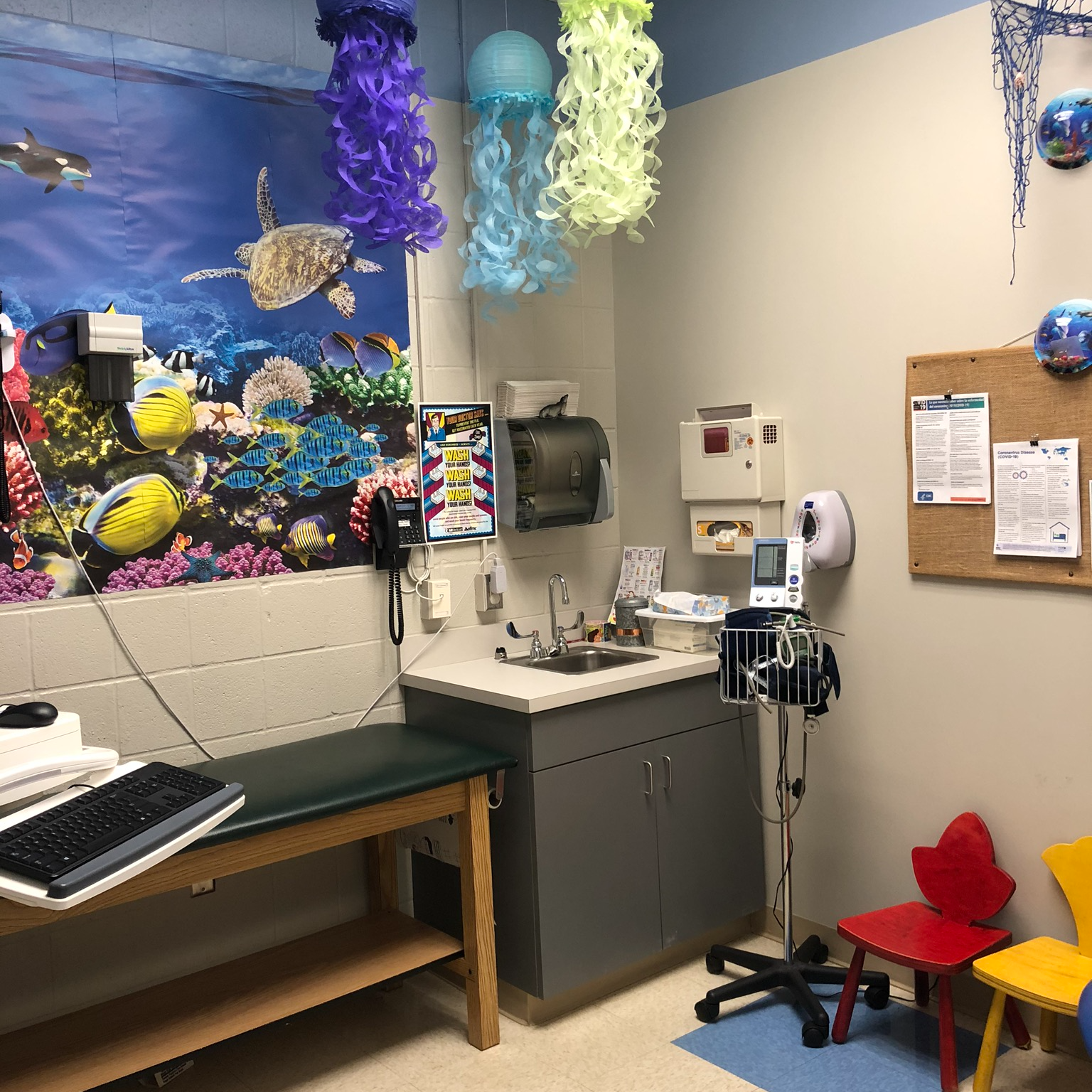 Exam room with underwater-themed wall hanging and paper jellyfish decorations hanging from ceiling. 