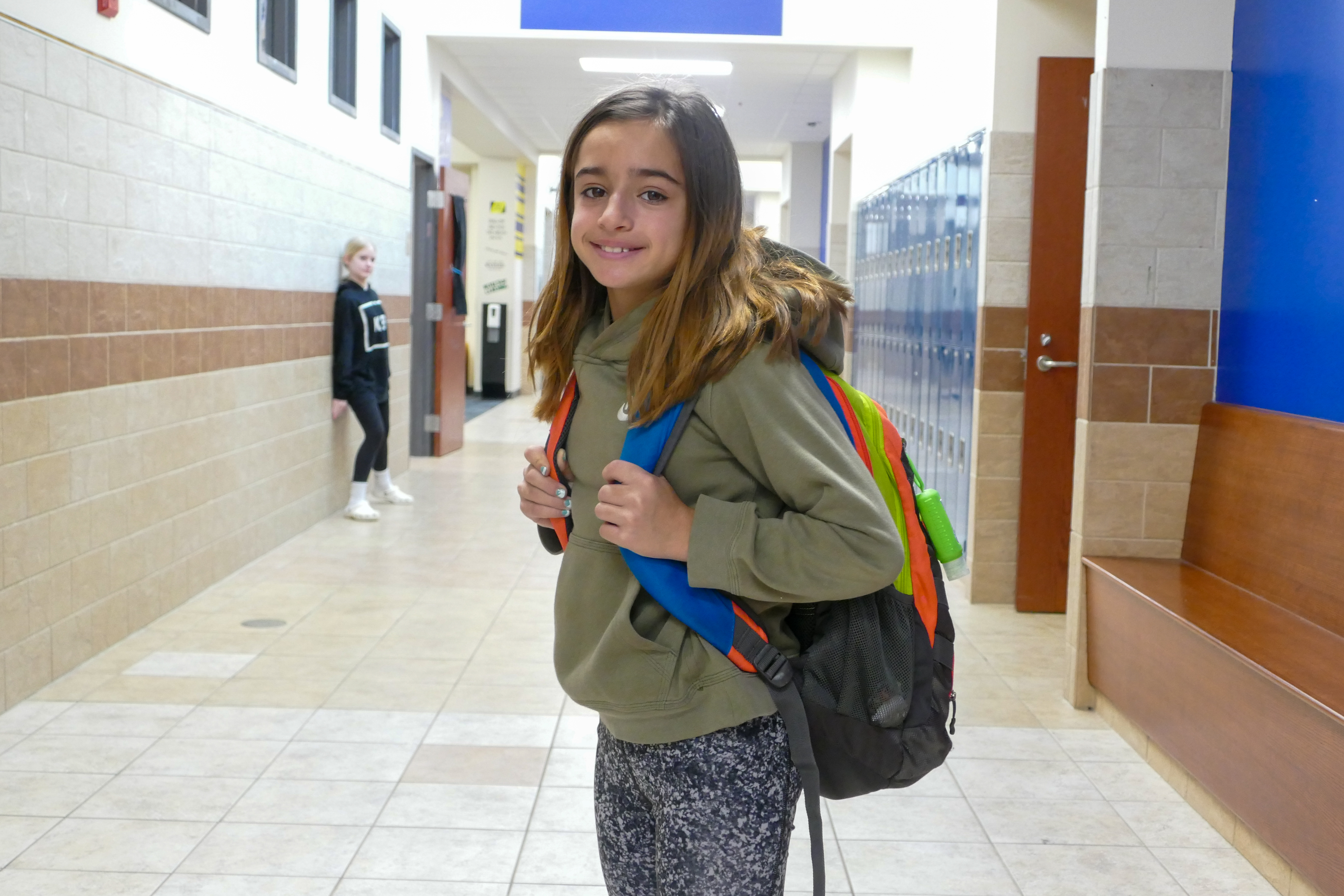 A student in the hallway poses with her backpack