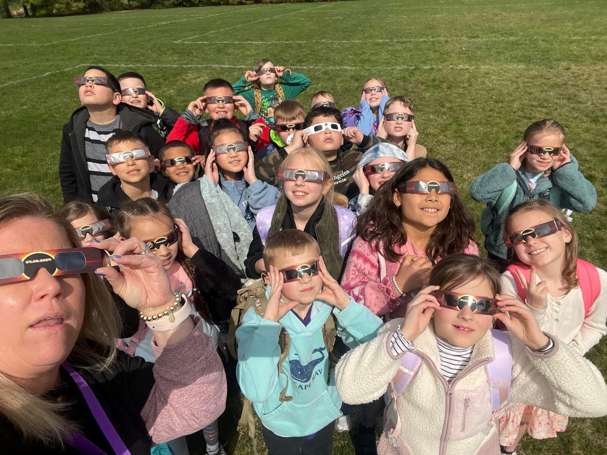 Teacher and students look at eclipse through eclipse glasses