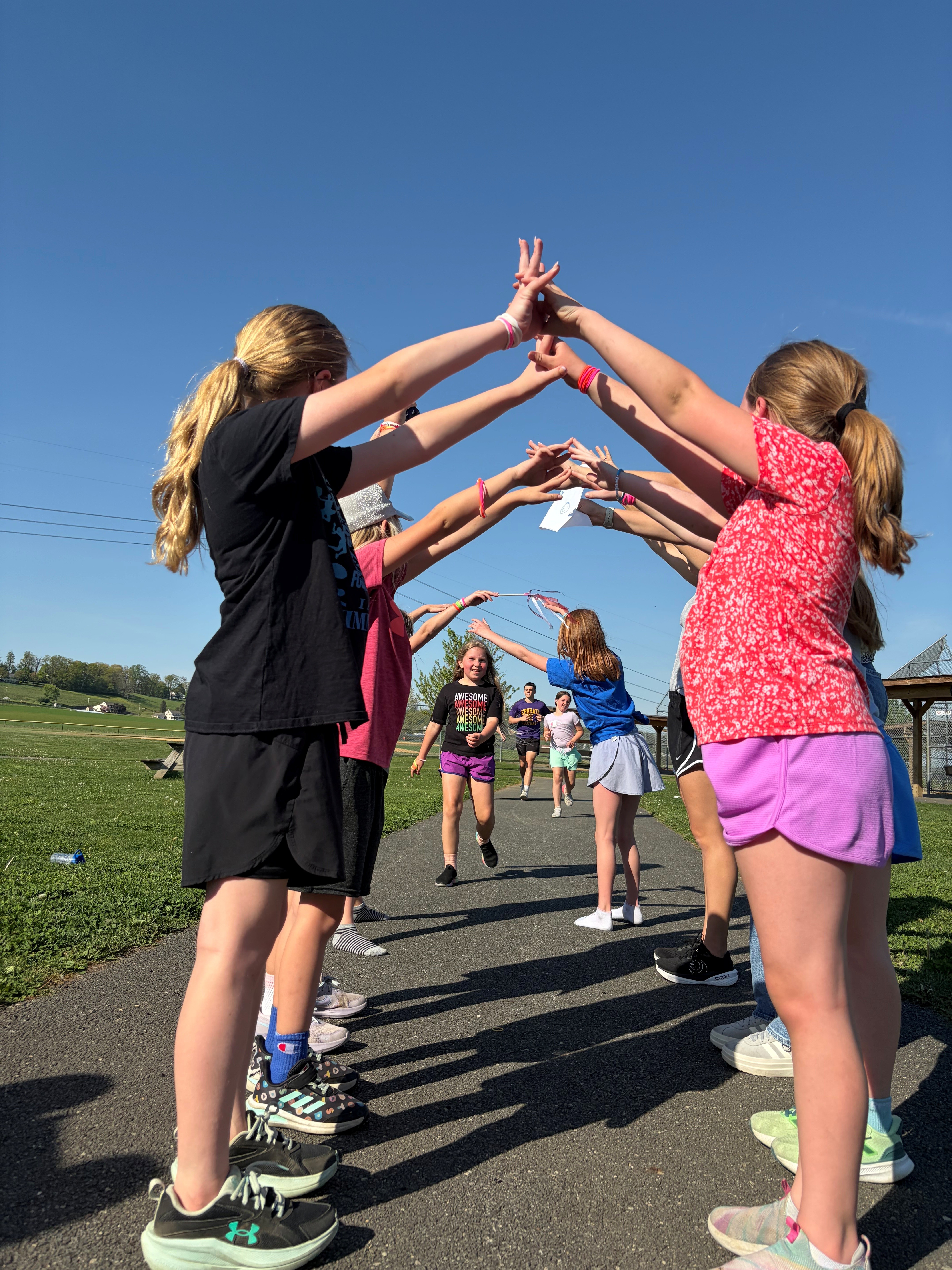 Girls on the Run make an arch while runners come to the finish line