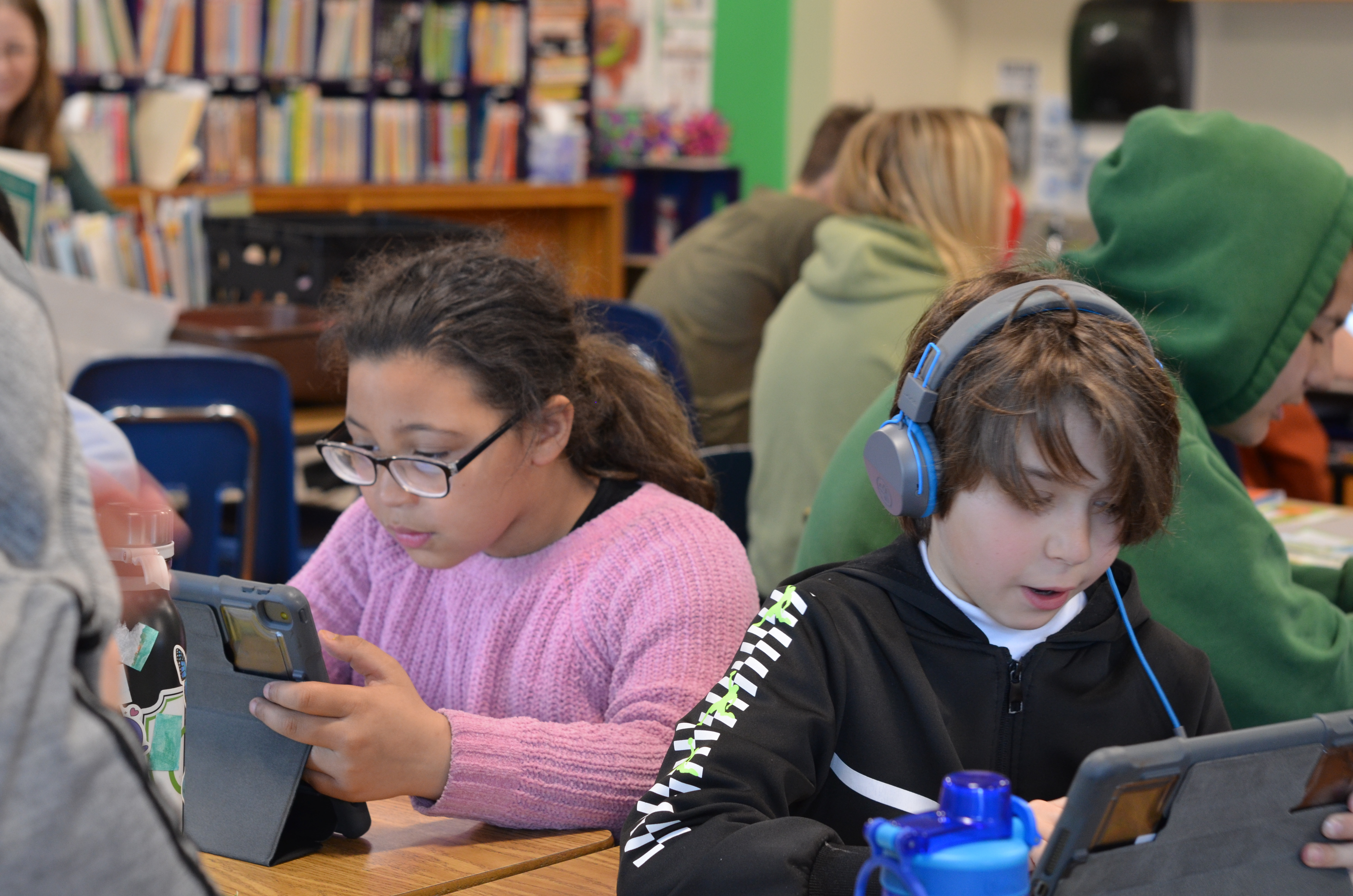 young boy and girl looking at ipads