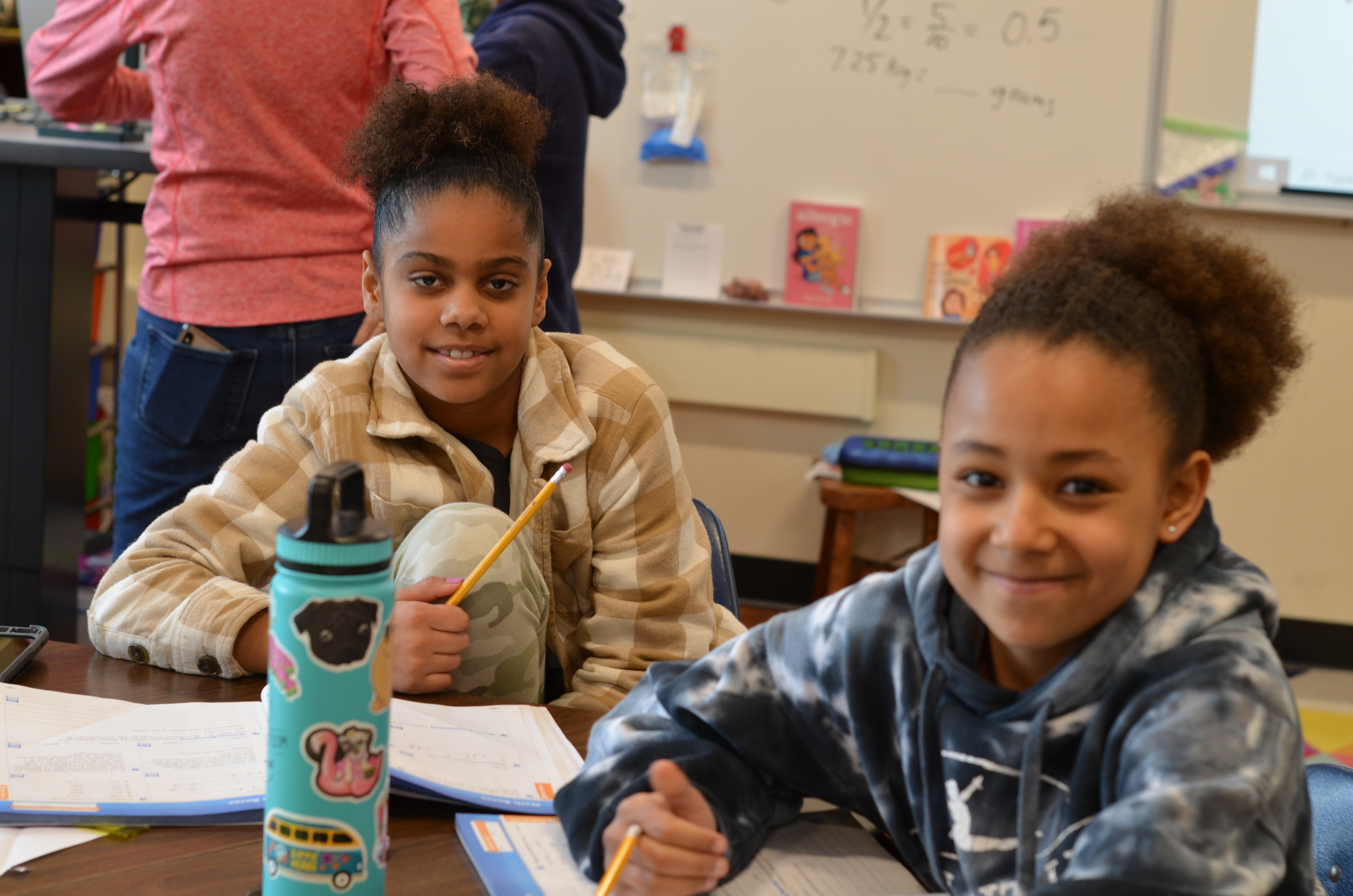 two female students smiling at camera in classroom
