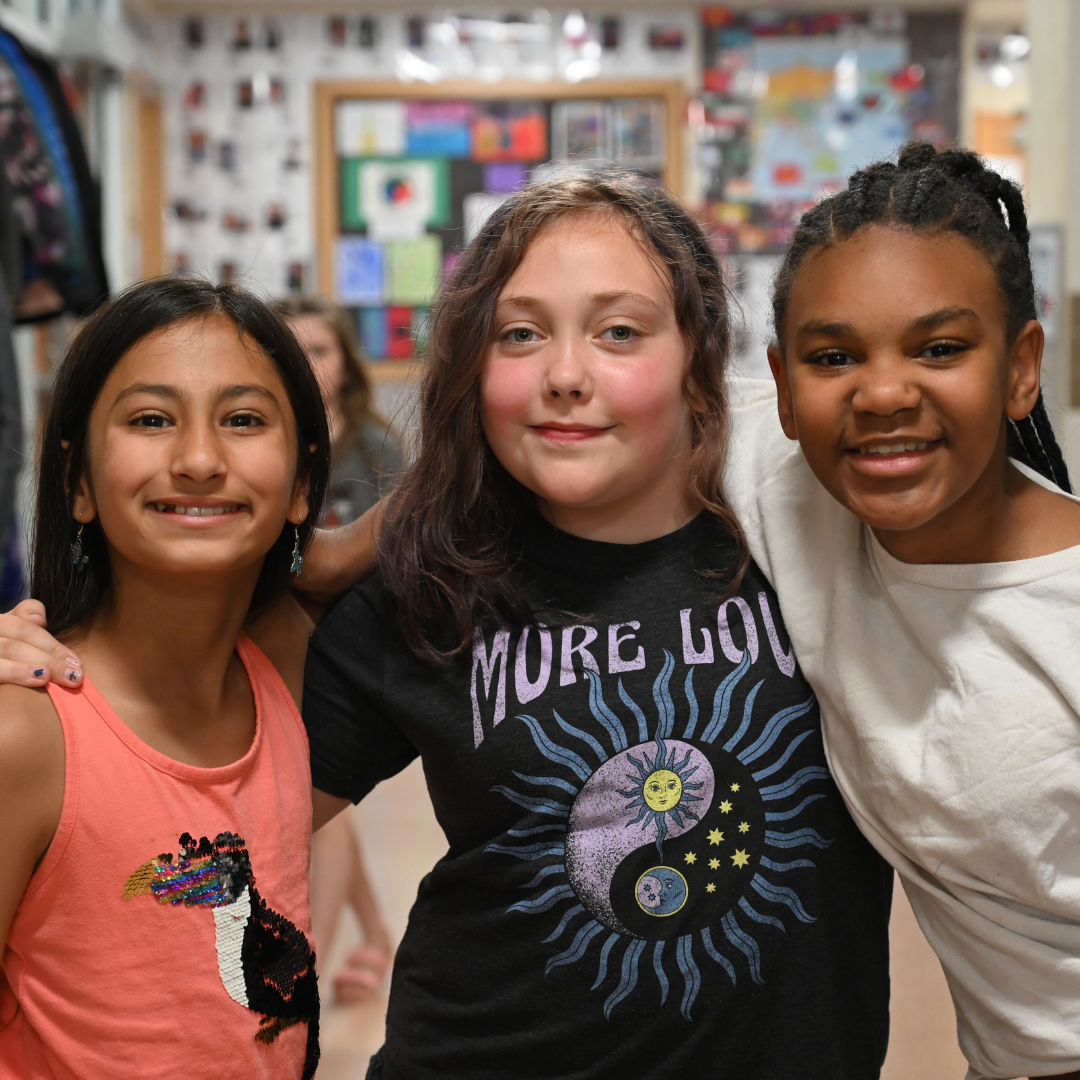 group of three students huddled in the hallway posing for a photo