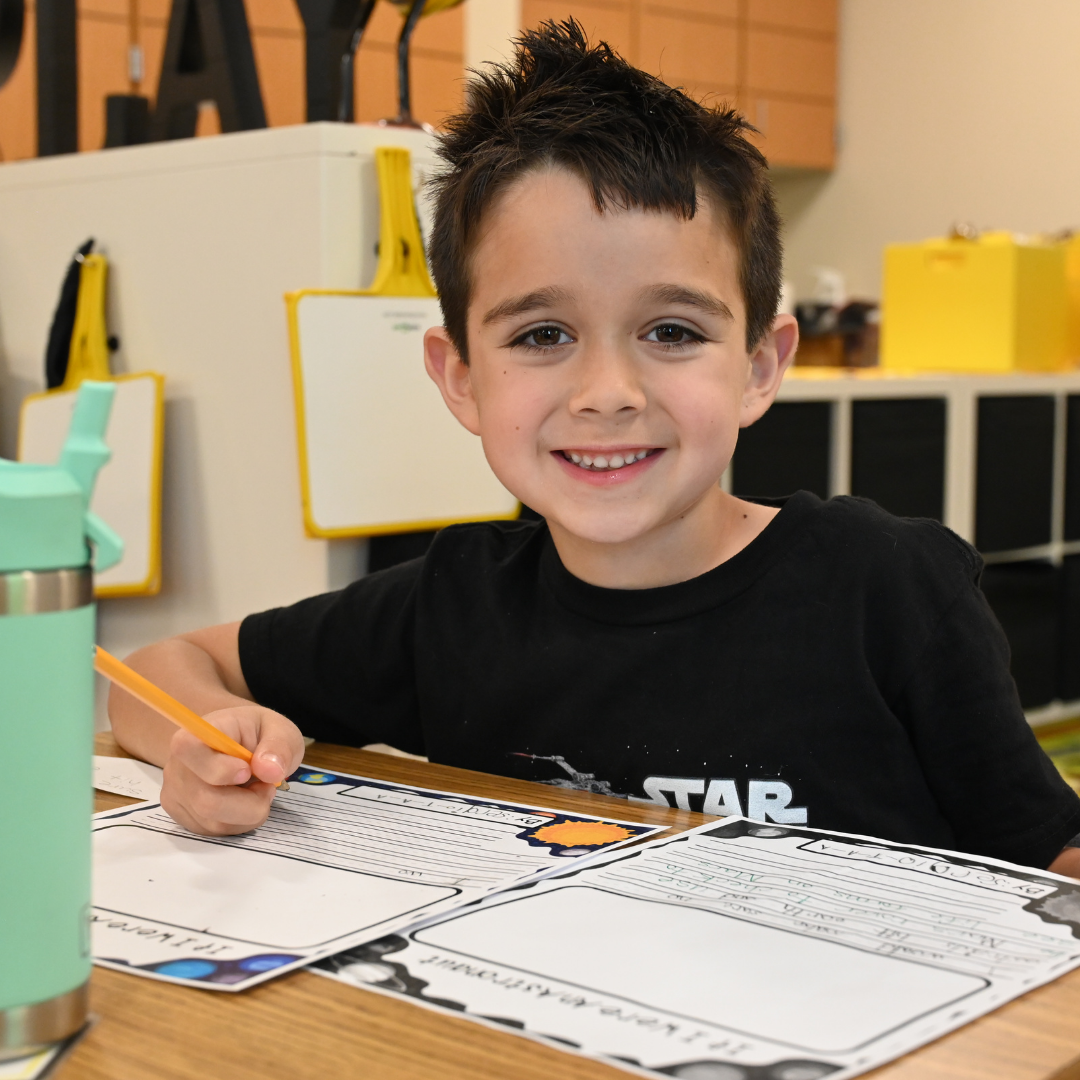 student at the table working on a writing assignment