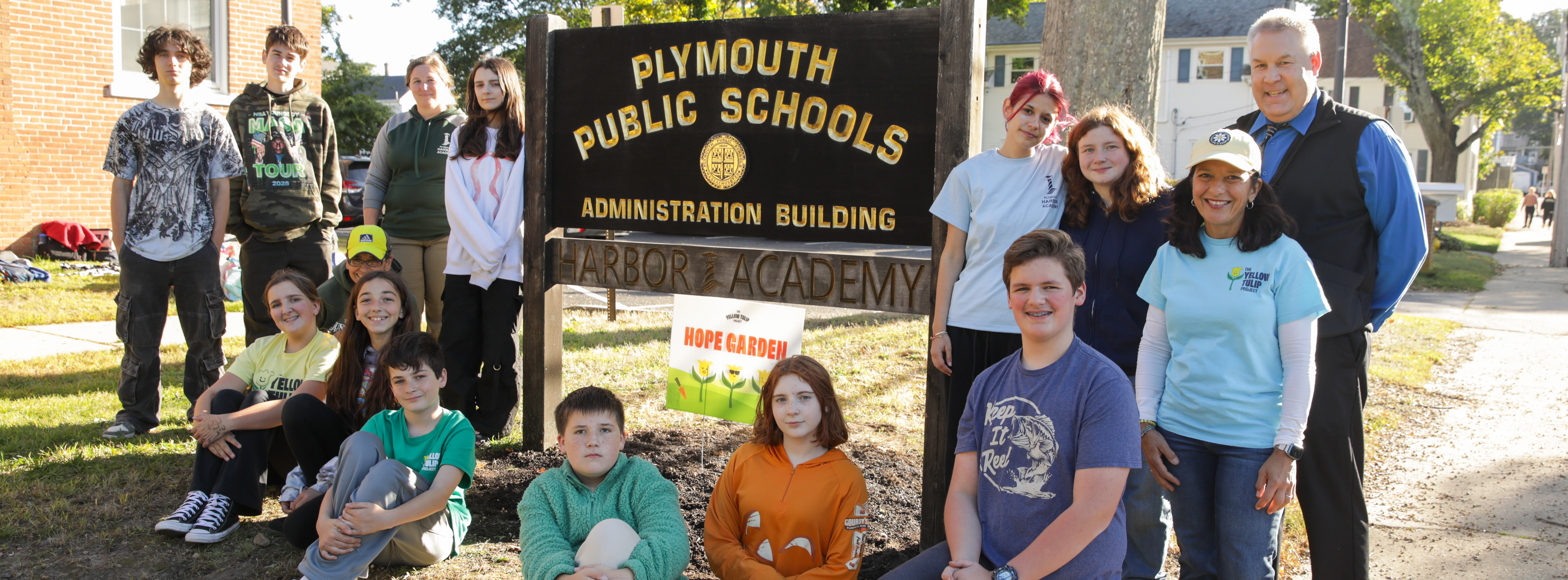 Students gather around a sign that reads "Hope Garden" for the Yellow Tulip Project