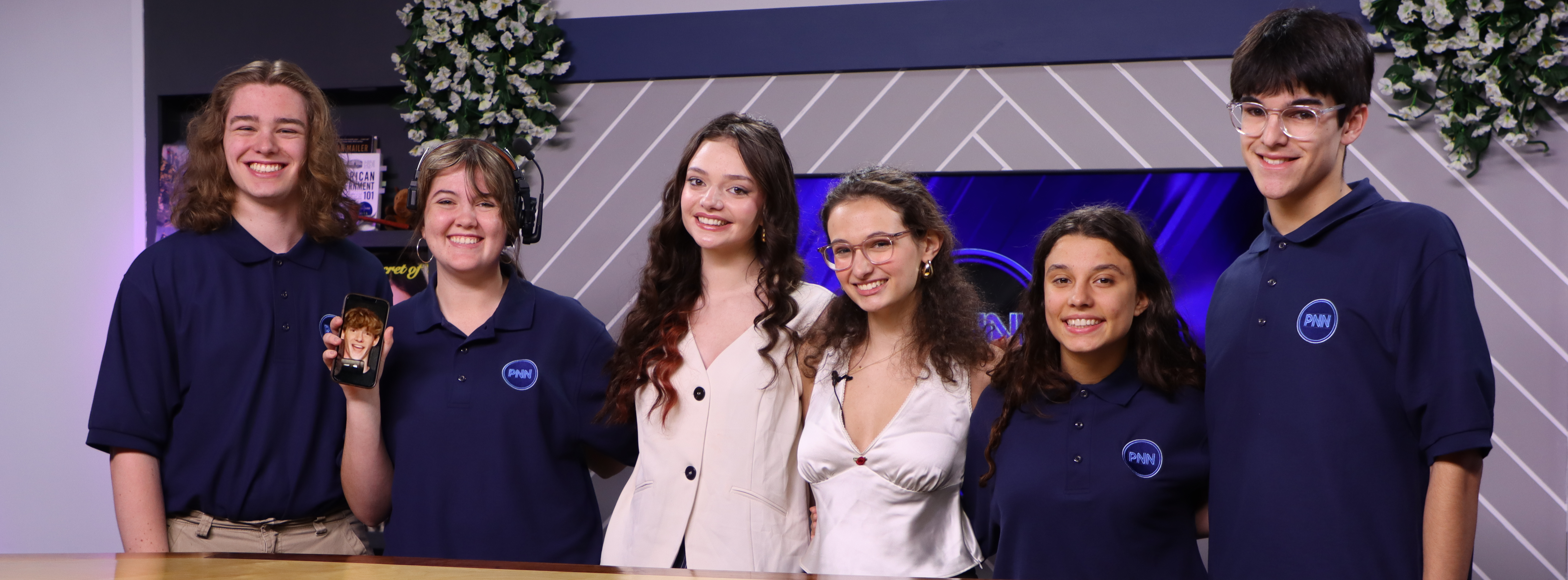 Students surrounding a news desk after a successful live show.