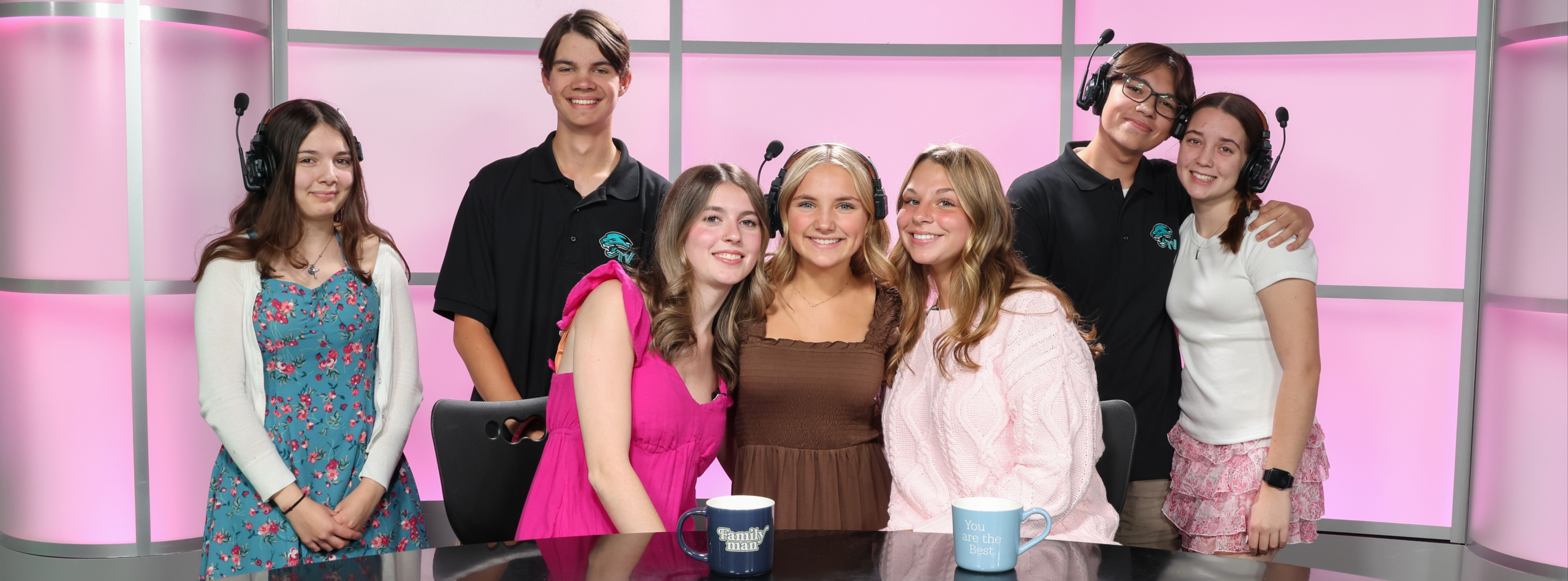 Students in Panther TV surround the desk and smile.
