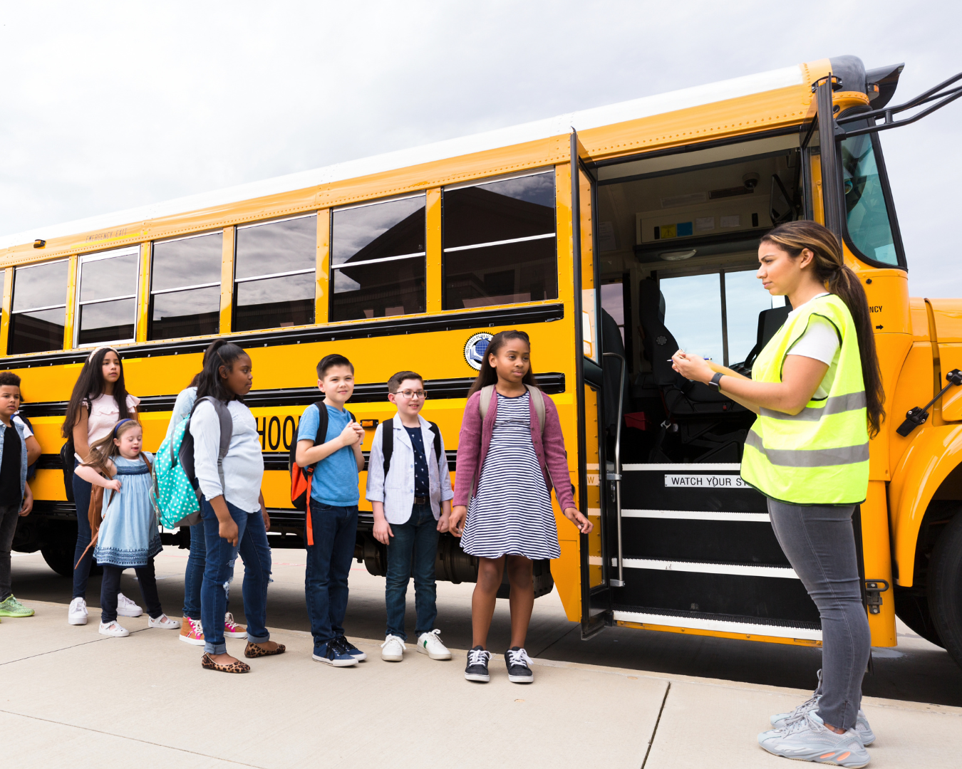 Students waiting in a line to get on a school bus
